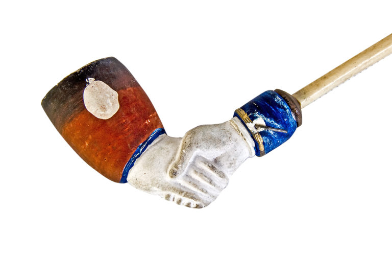 Clay pipe shaped and painted to look like two hands shaking.